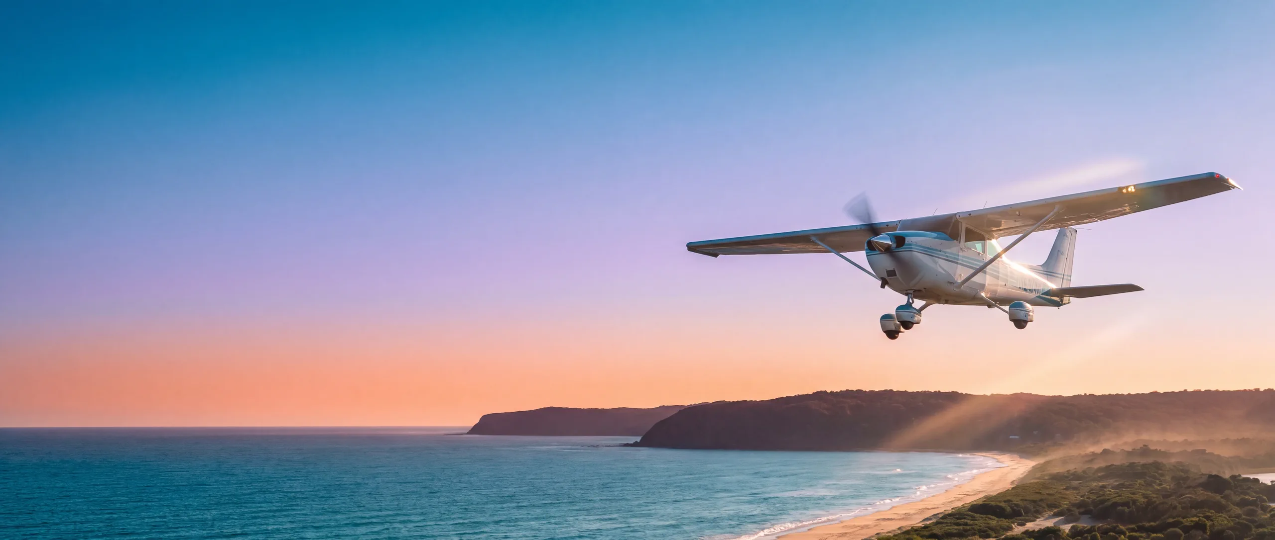 A Cessna 172 climbing away over the Australian coast at first light, the sky running from cyan through violet to coral.
